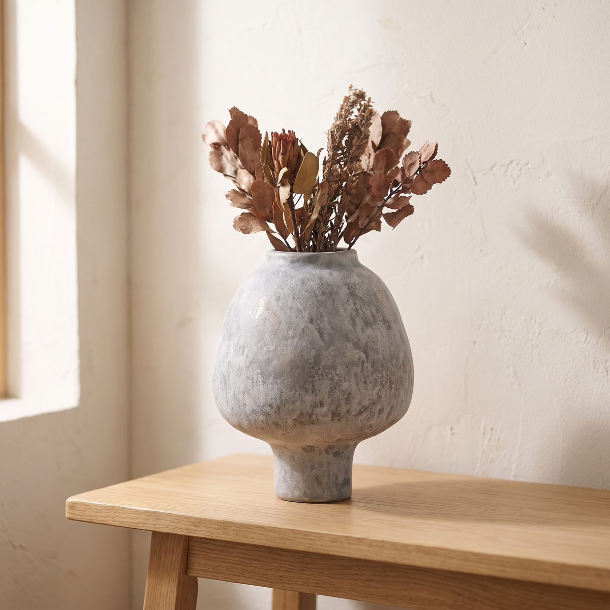 Handmade grey stoneware pedestal vase displayed in a warm modern interior