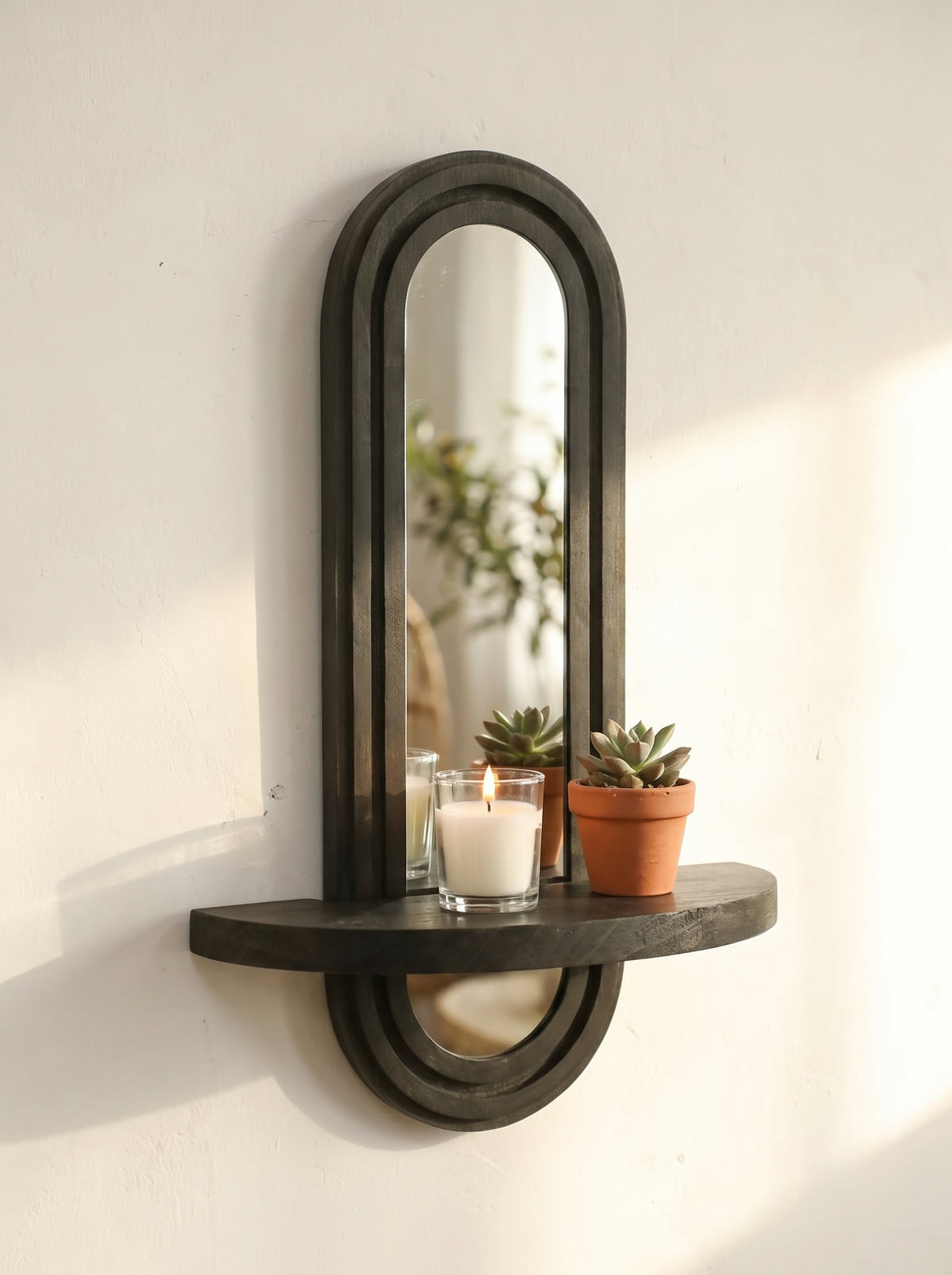 Arched mirror shelf holding a candle and a plant