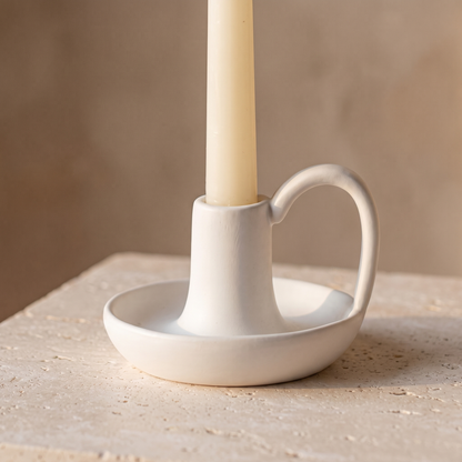 Minimal ceramic taper candle holder with handle displayed in a warm modern interior