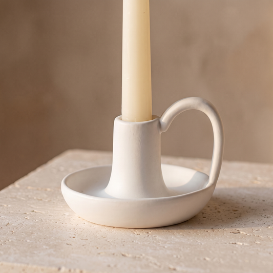 Minimal ceramic taper candle holder with handle displayed in a warm modern interior