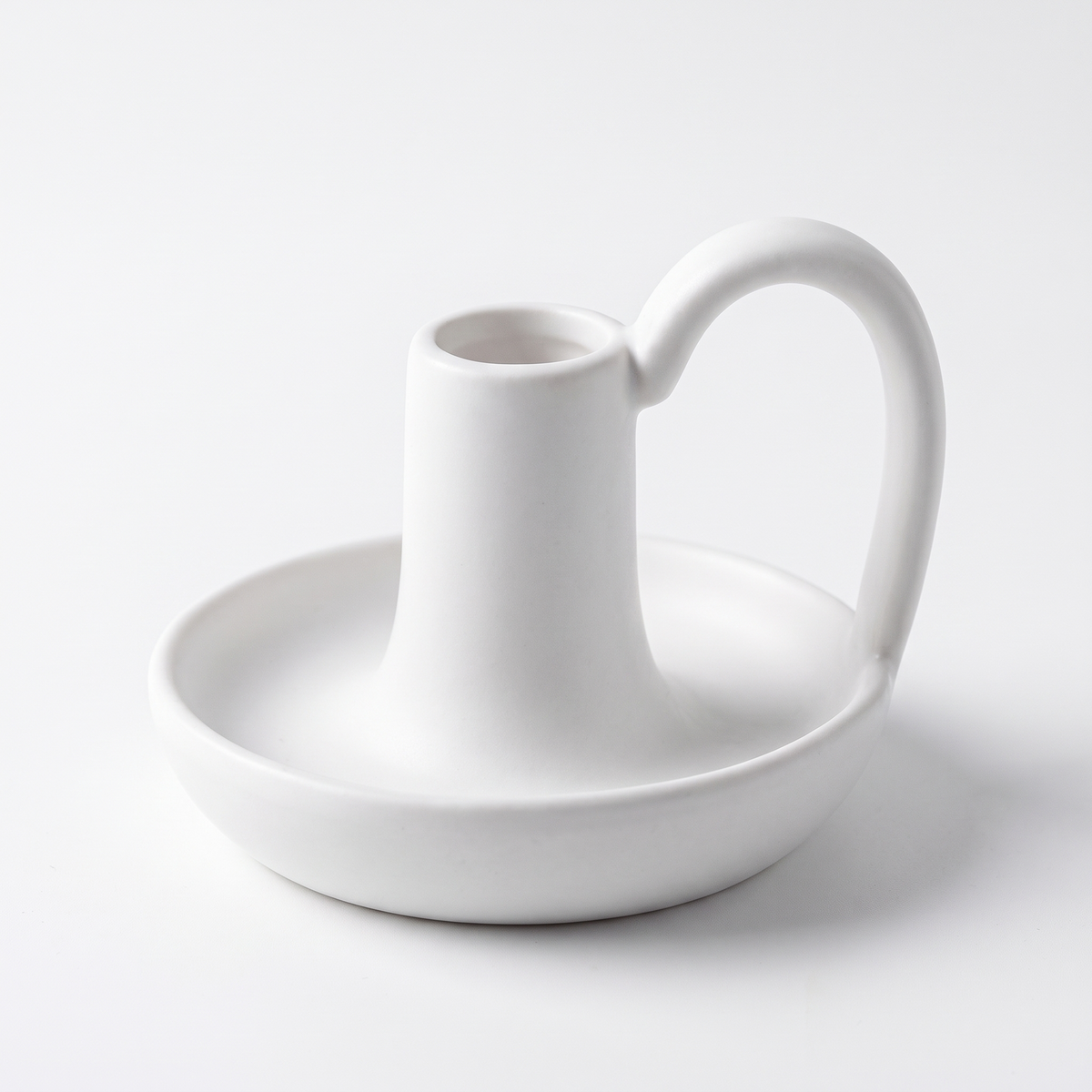 Minimal ceramic taper candle holder with handle on a white background